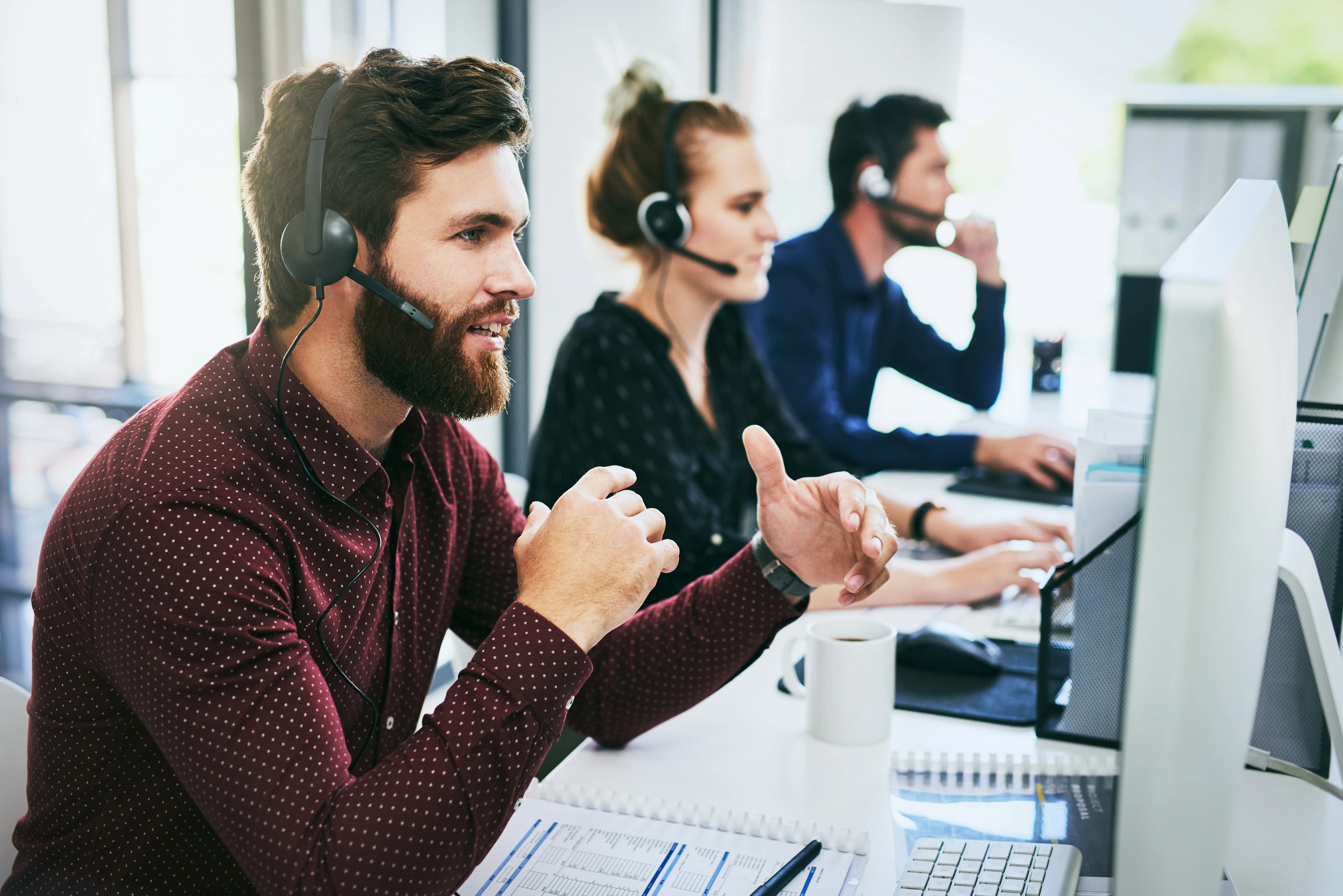 three members of staff working in an office all with headsets on