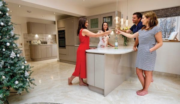 4 people having christmas drinks on a tiled kitchen floor without shoes on