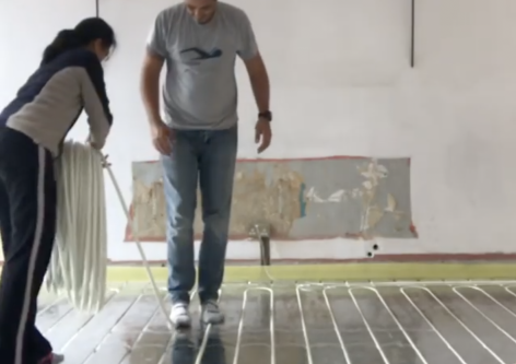 A couple showing how easy it is to lay underfloor heating pipe