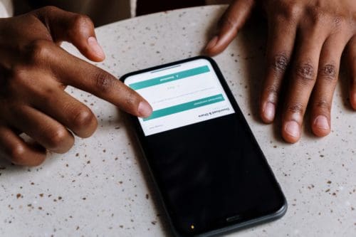 hands using a smartphone to fill out a form that's on a table table