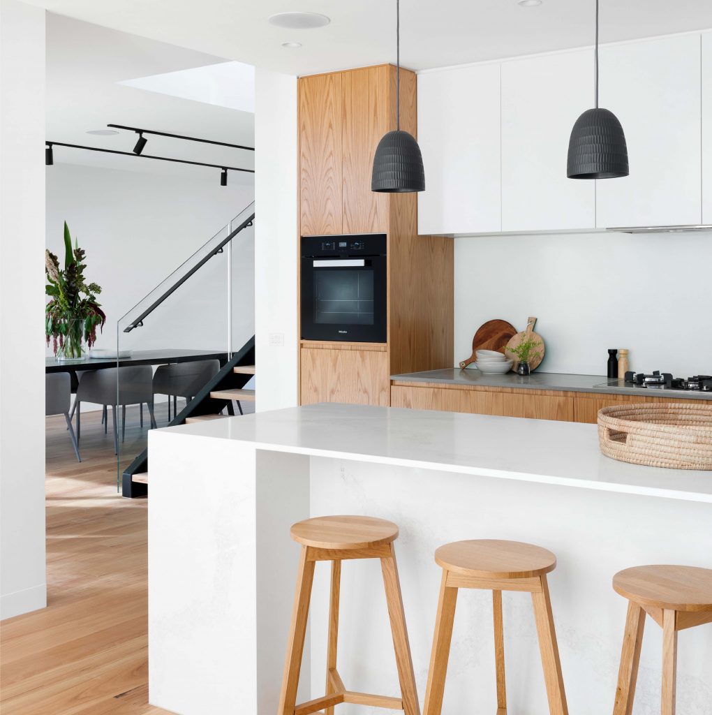a modern and simplistic kitchen with three stools at a breakfast bar